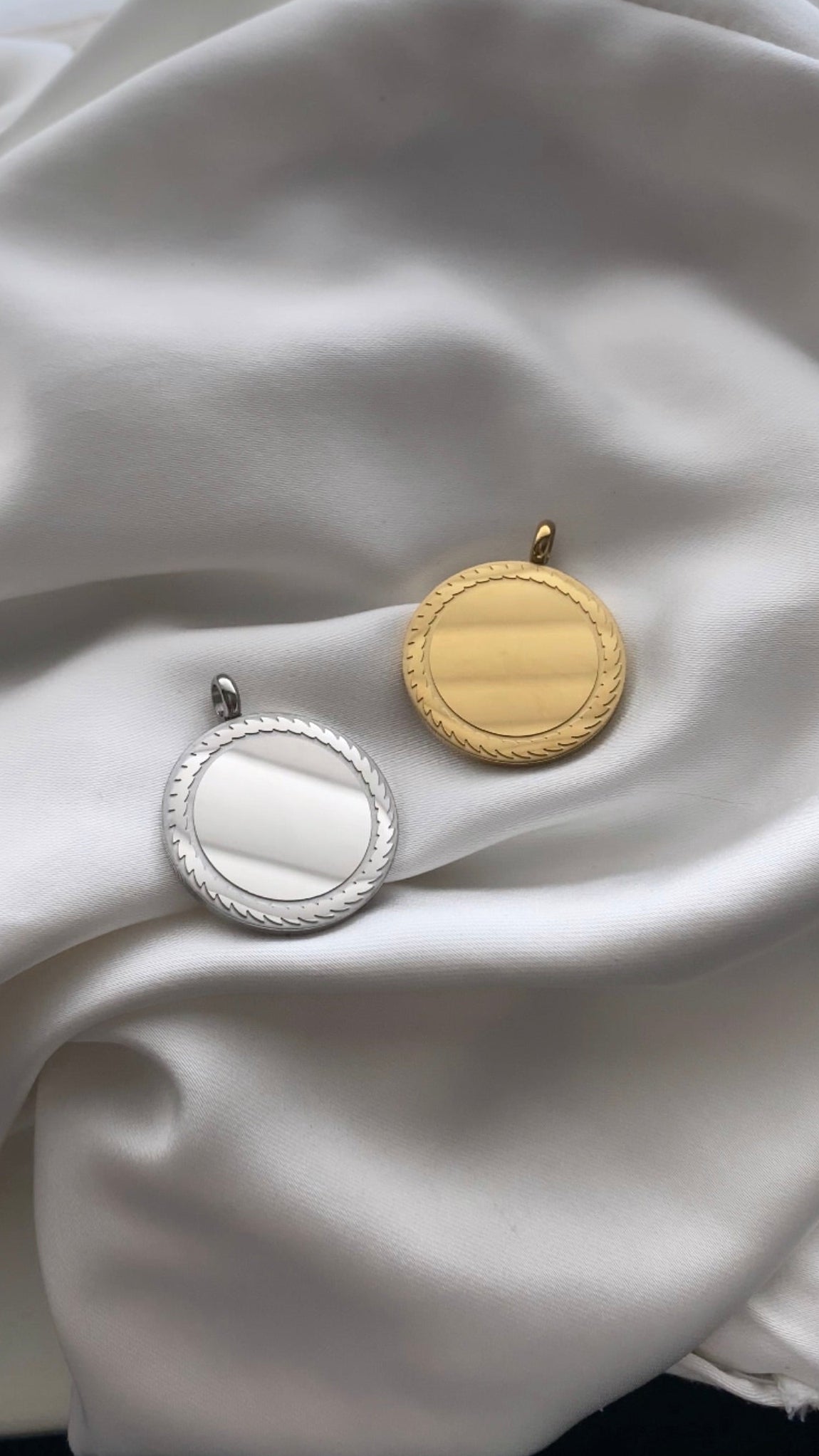 Gold and silver round earrings on a white fabric background