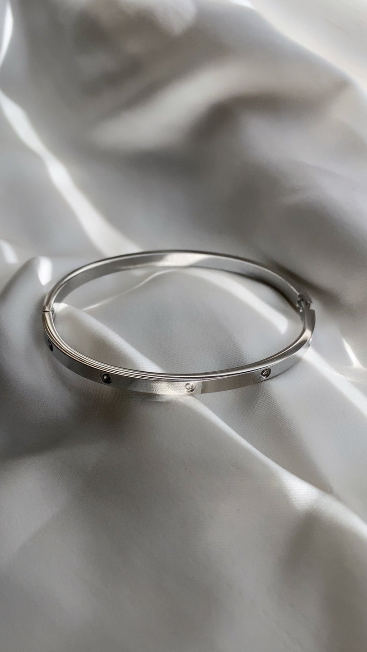Silver bracelet on a white fabric background