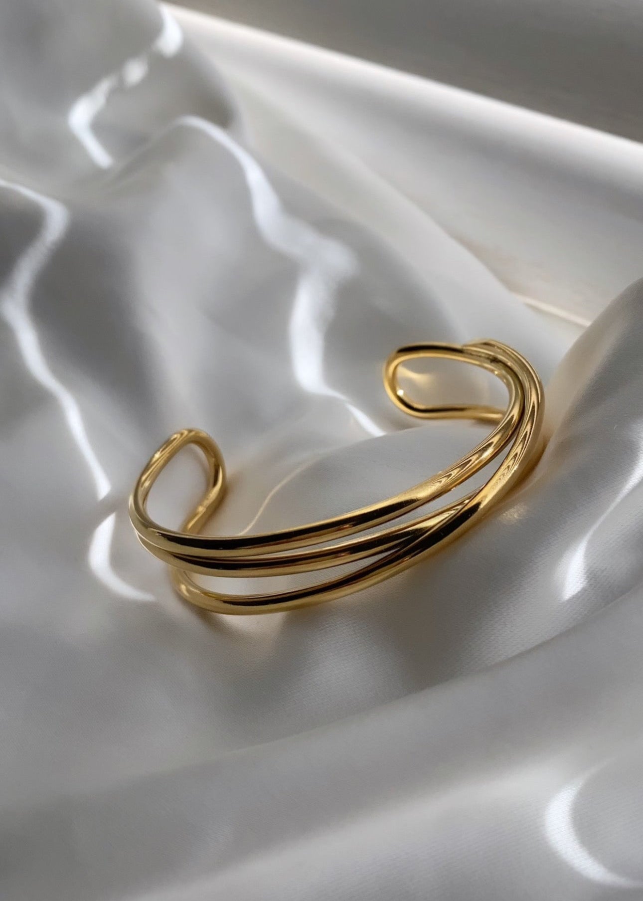 “Gouden open armband dames – minimalistische stainless steel bangle met dubbele lijnen op satijnen achtergrond | Haydée Jewelry”