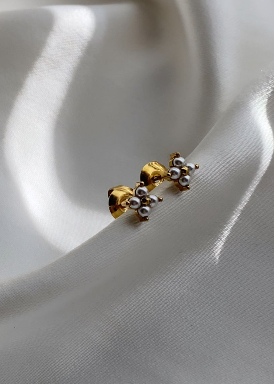 Gold and silver earrings on a white fabric background