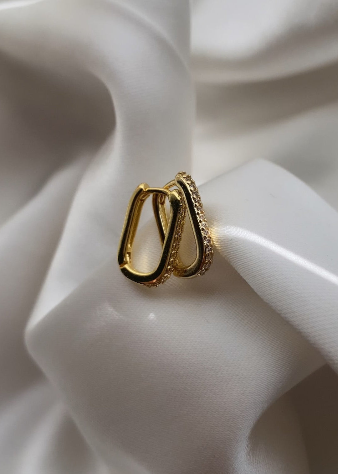 Gold hoop earrings on a white fabric background