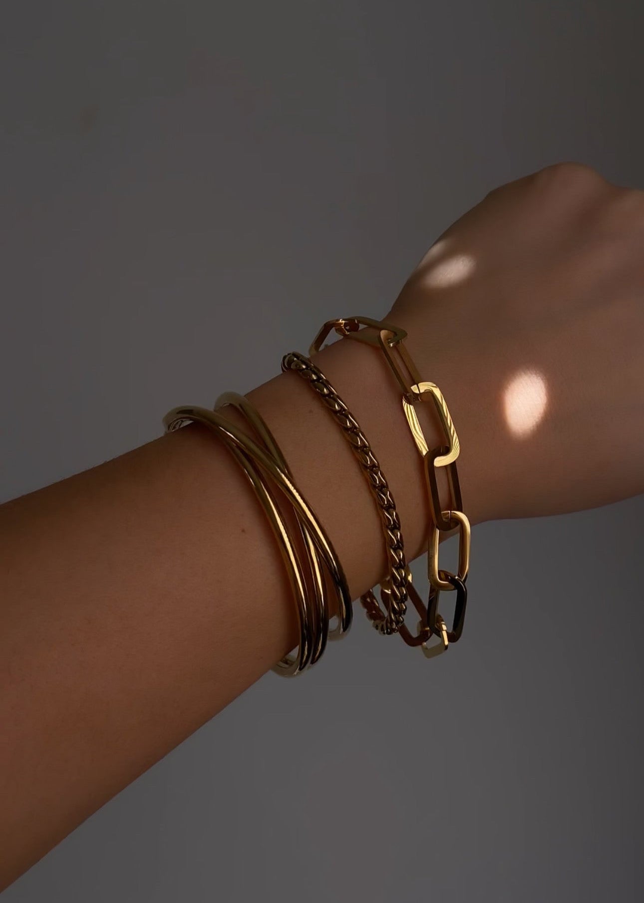 Set van gouden armbanden om pols, stainless steel bangles en schakel armband in layered look.