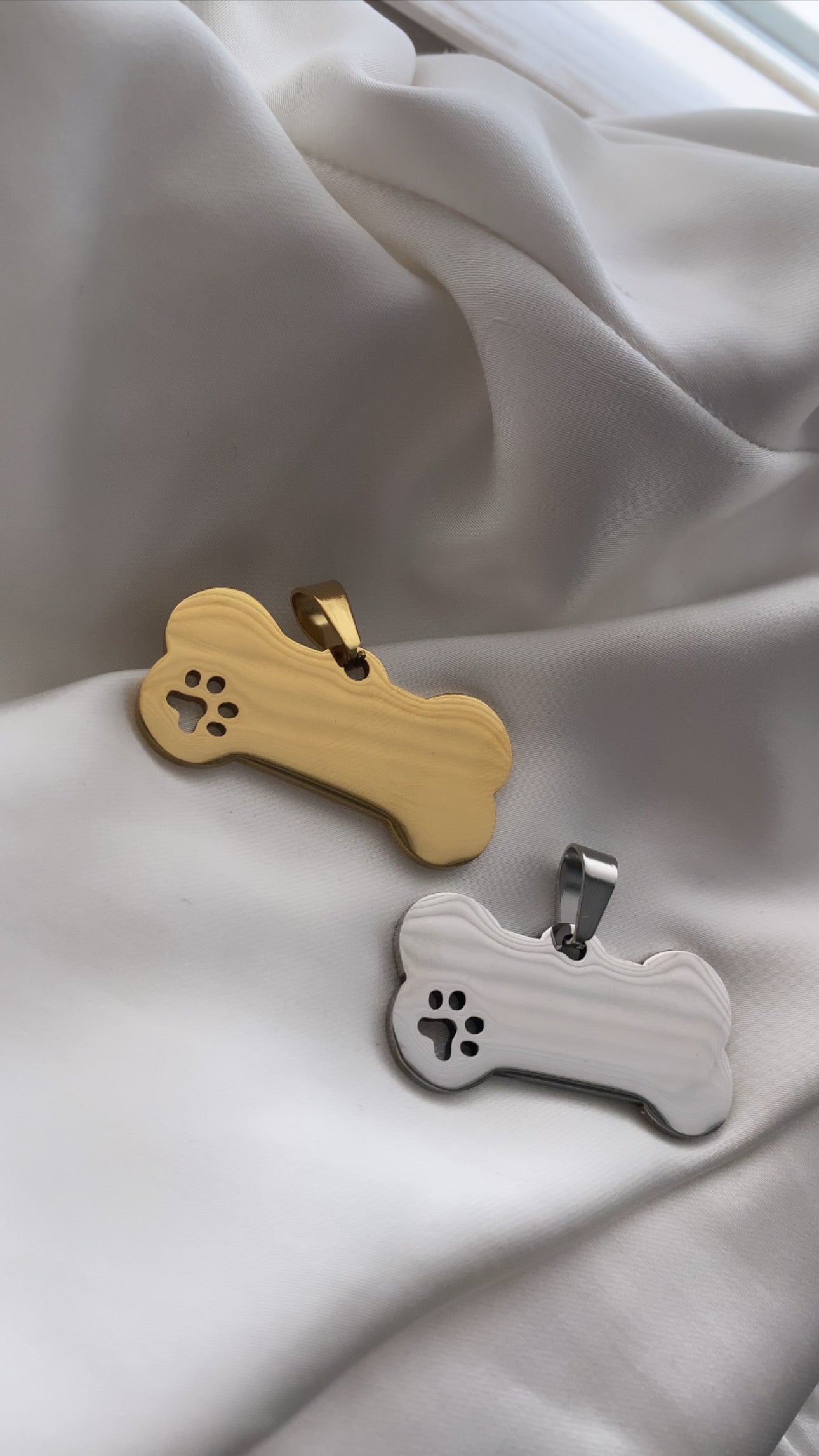Two dog bone-shaped pendants on a light fabric background