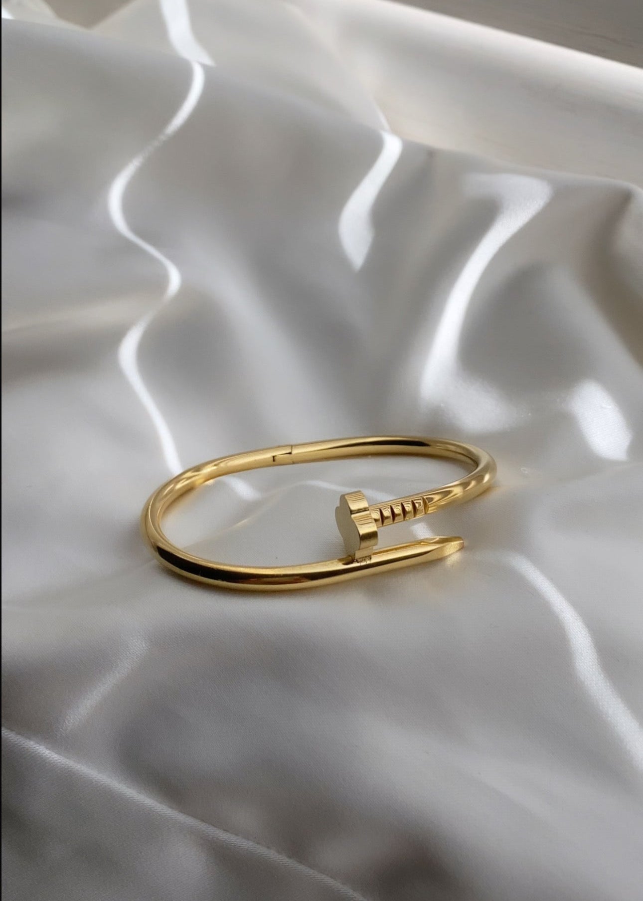 “Gouden open armband met minimalistisch spijkerdesign op ivoorkleurig satijnen doek – Haydée Jewelry”