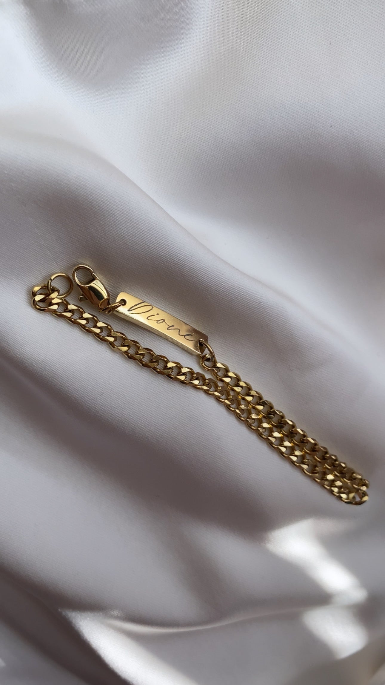 Gold chain bracelet on a white fabric background