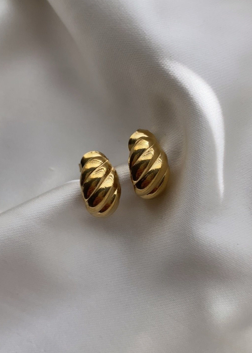 Gold earrings on a white fabric background