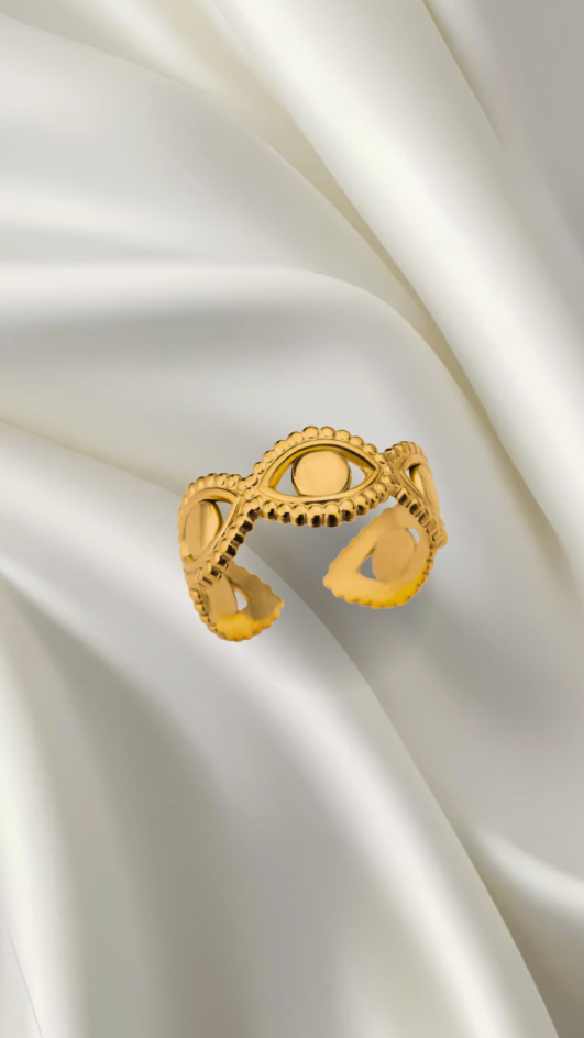Gold ring with intricate design on a white satin background