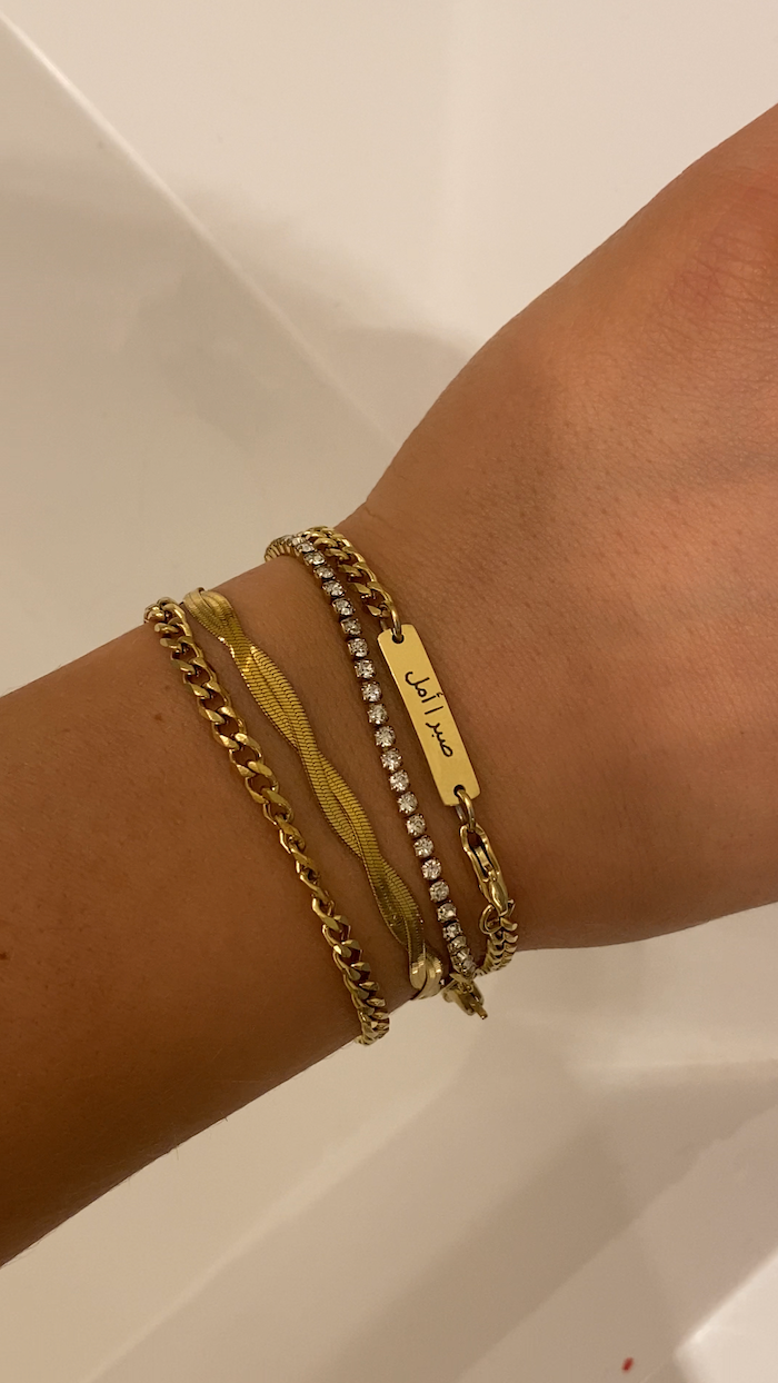 Gold bracelets on a wrist against a neutral background