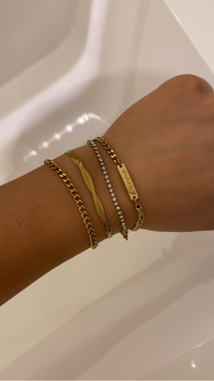 Hand wearing multiple gold bracelets on a white background