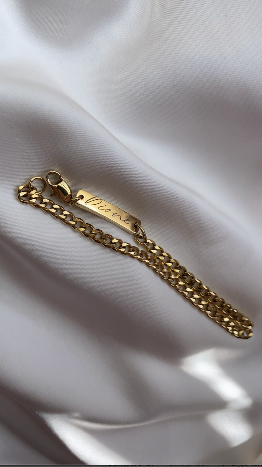 Gold chain bracelet on a white fabric background