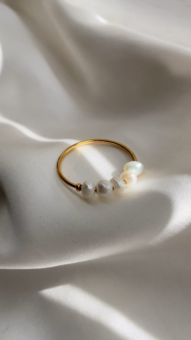 Gold ring with pearls on a white fabric background