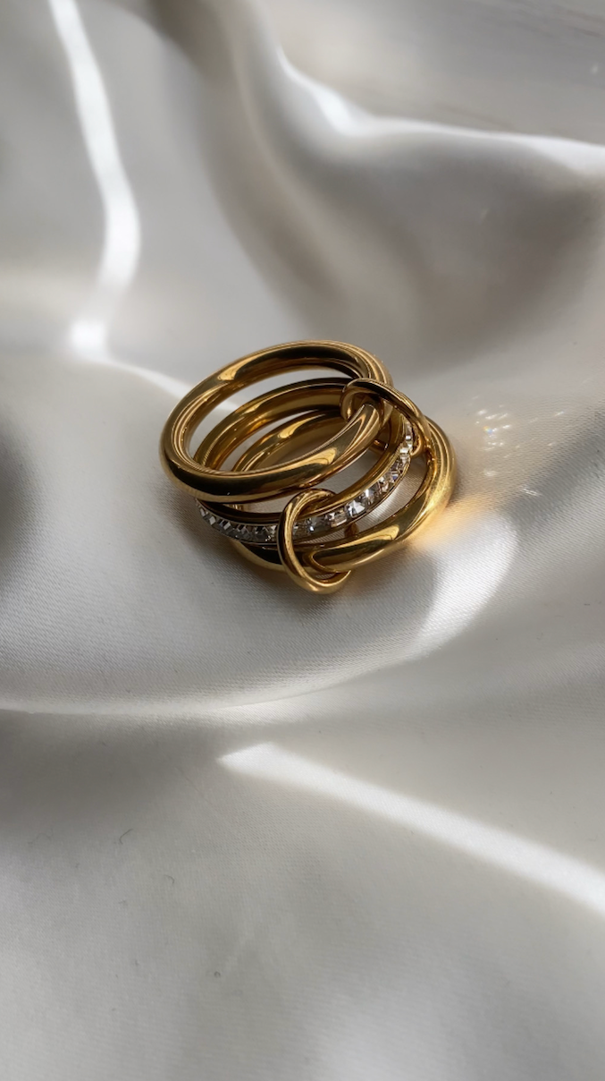 Gold ring with embedded stones on a textured white surface