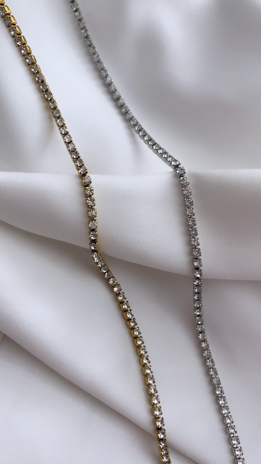 Two diamond necklaces on a white fabric background