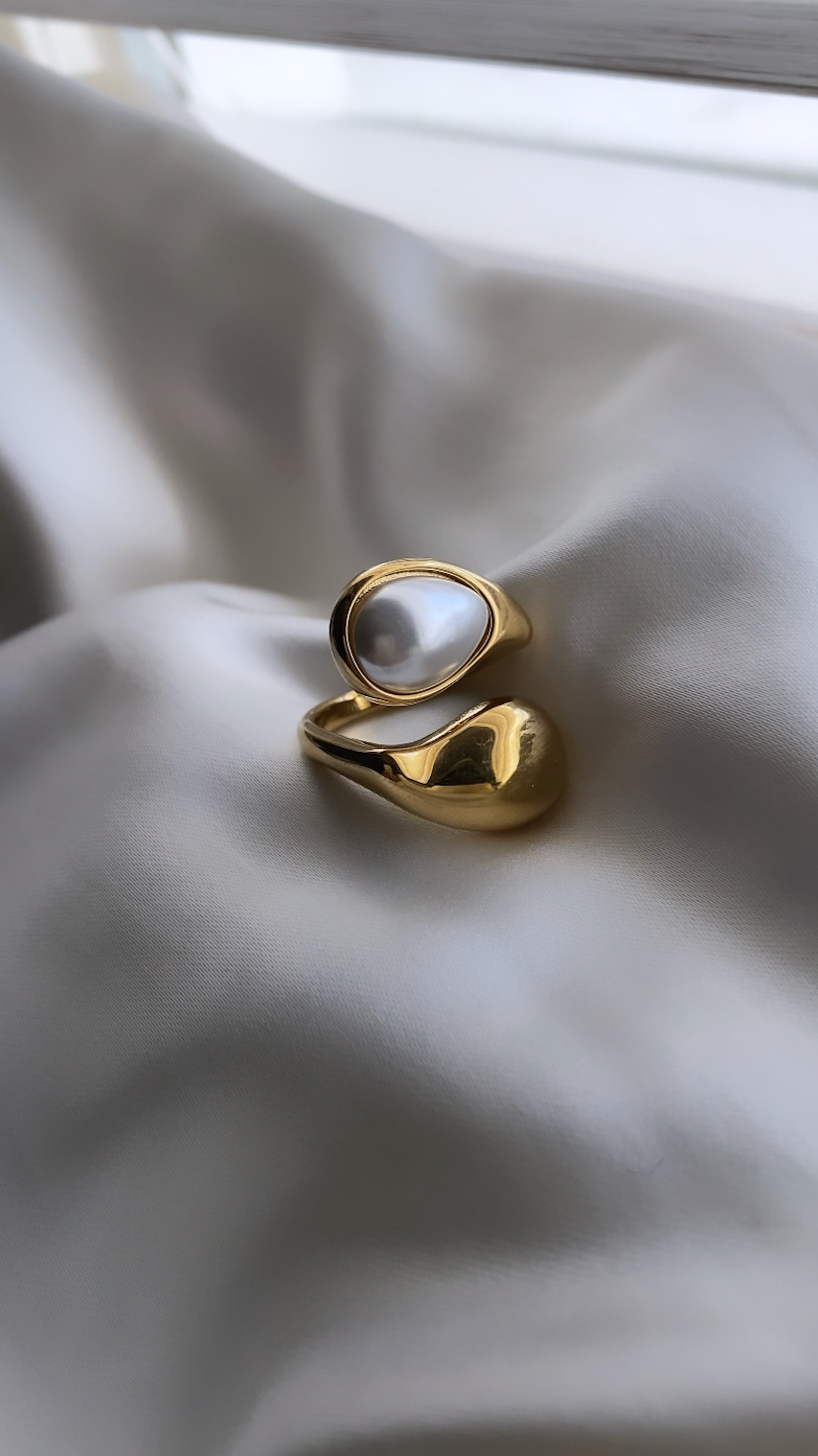 Gold ring with a central gemstone on a light fabric background