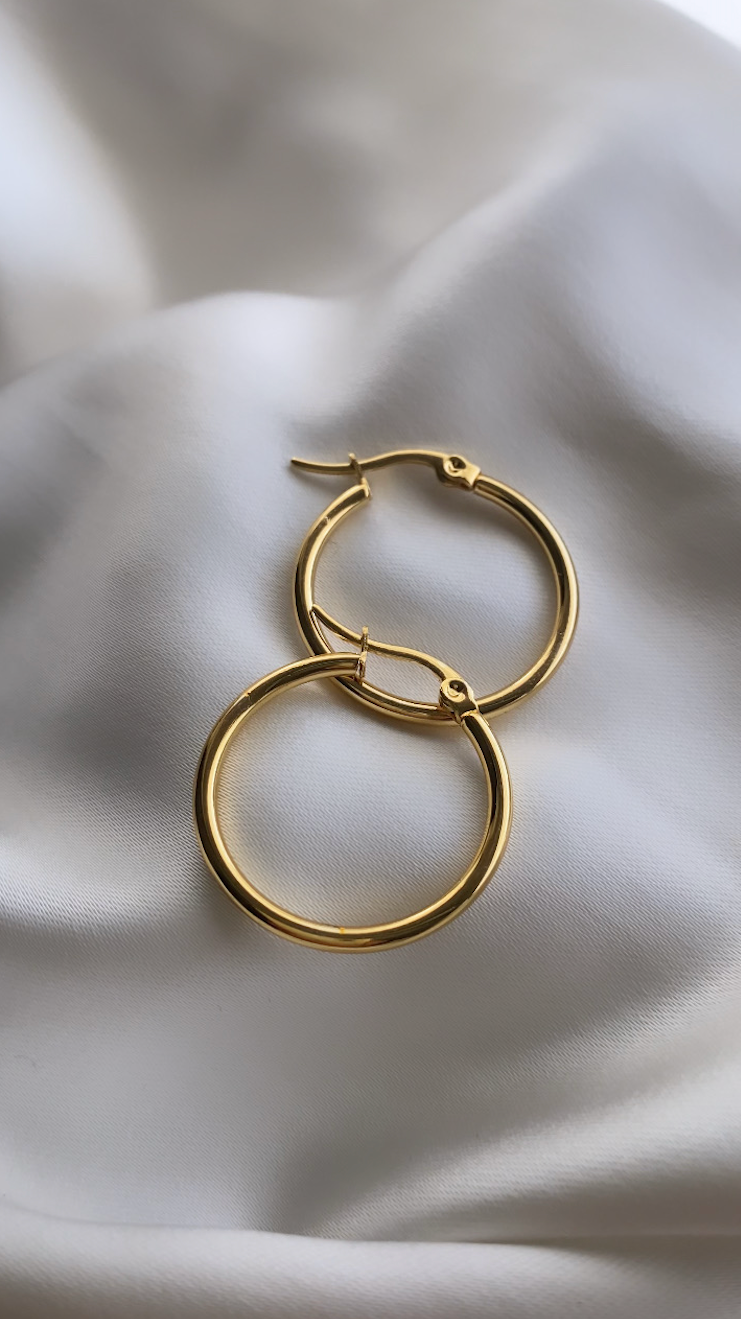 Gold hoop earrings on a soft white fabric background