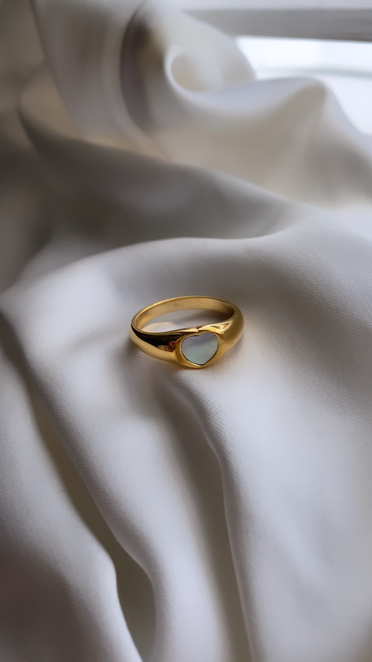 Gold ring with a heart-shaped cutout on white fabric