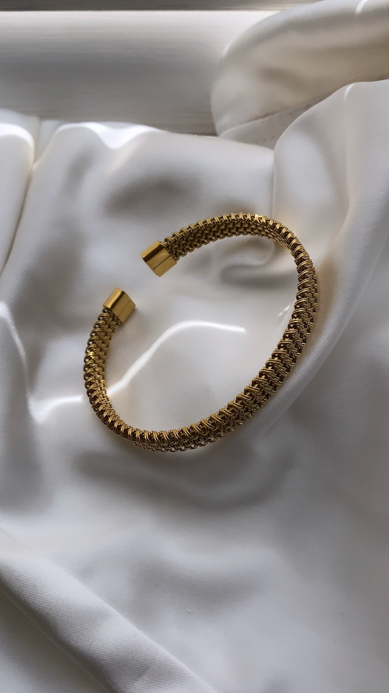 Gold bracelet on a white fabric background