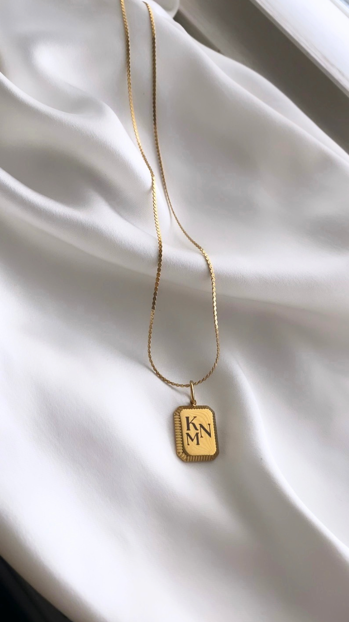 Gold necklace with a pendant on a white fabric background