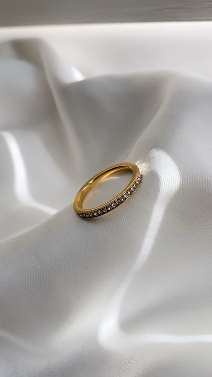 Gold ring with small stones on a white fabric background