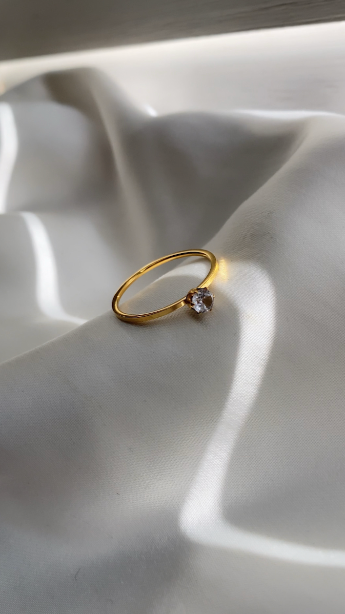 Gold ring with a diamond on a white fabric background