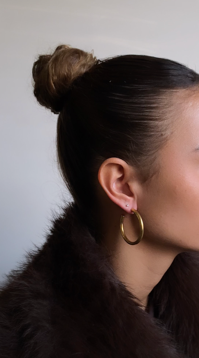 Woman wearing a dark fur coat with a plain background